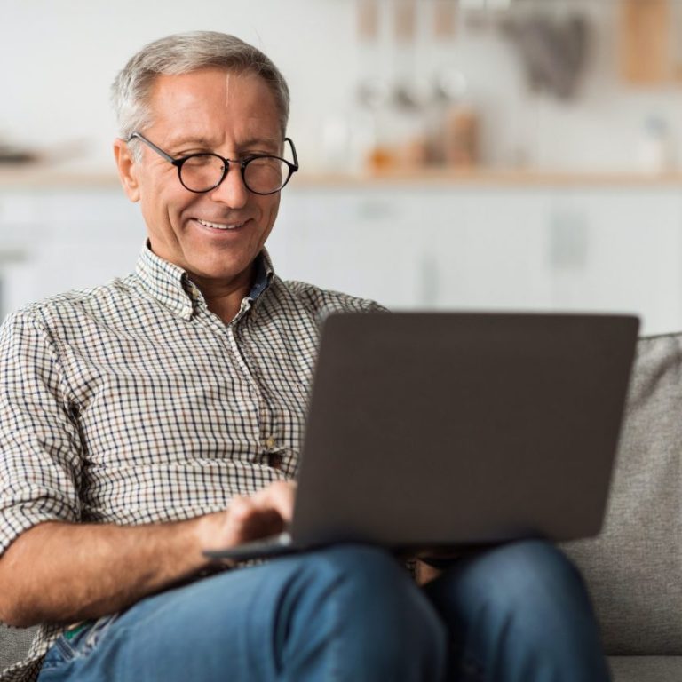 happy senior man using laptop browsing internet sitting at home Lift Parts Unlimitted